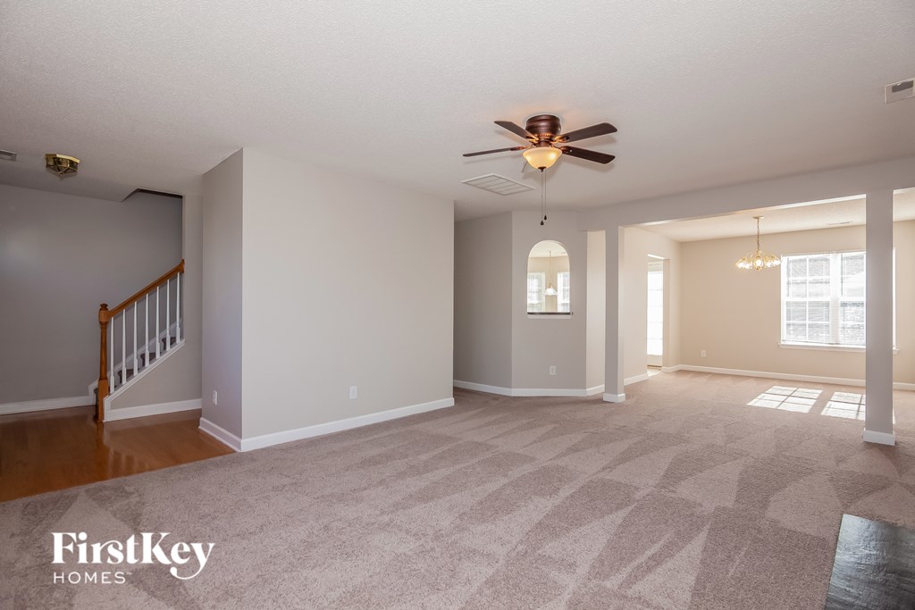 A spacious room with a carpeted floor and a ceiling fan.