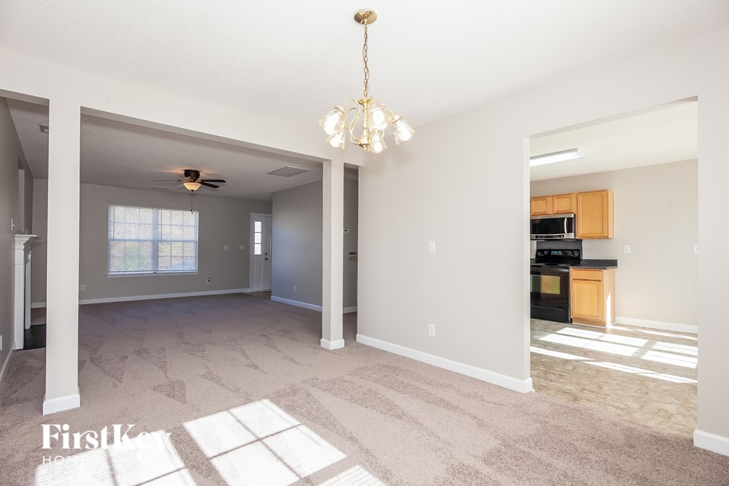 A spacious living room with a chandelier and a ceiling fan.
