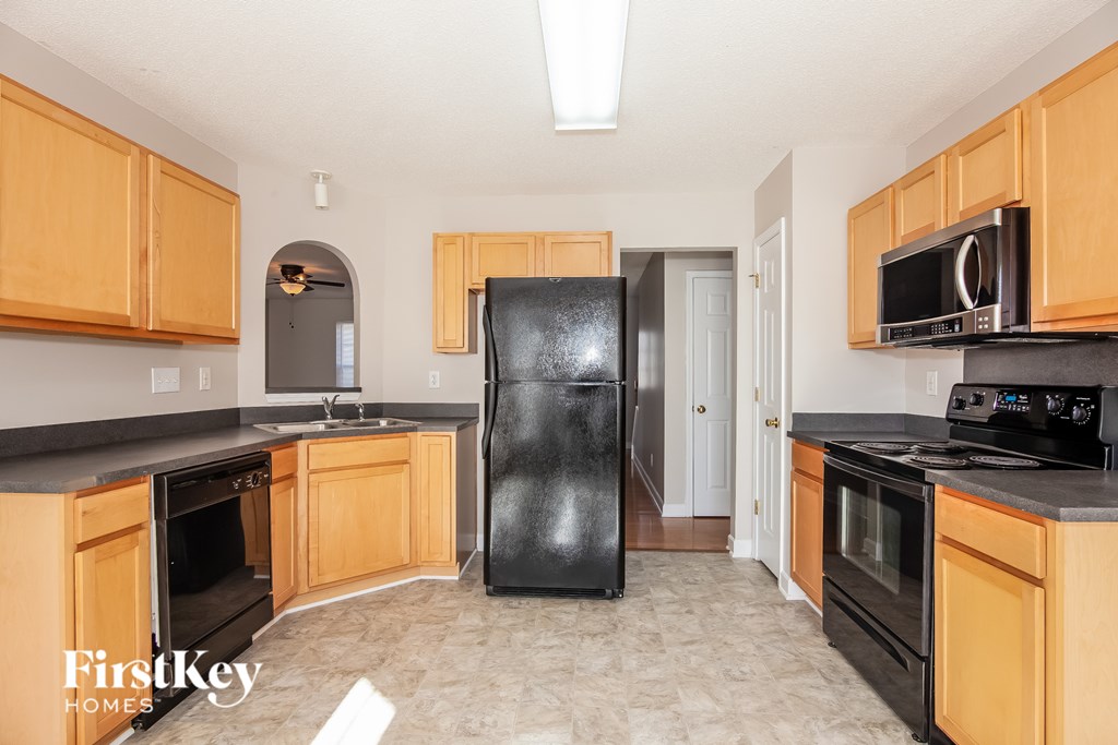 A kitchen with wooden cabinets and a black fridge.