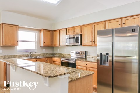 a kitchen with granite counter tops and wooden cabinets and stainless steel appliances