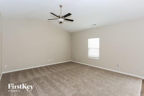 A spacious room with a ceiling fan and a window with blinds.