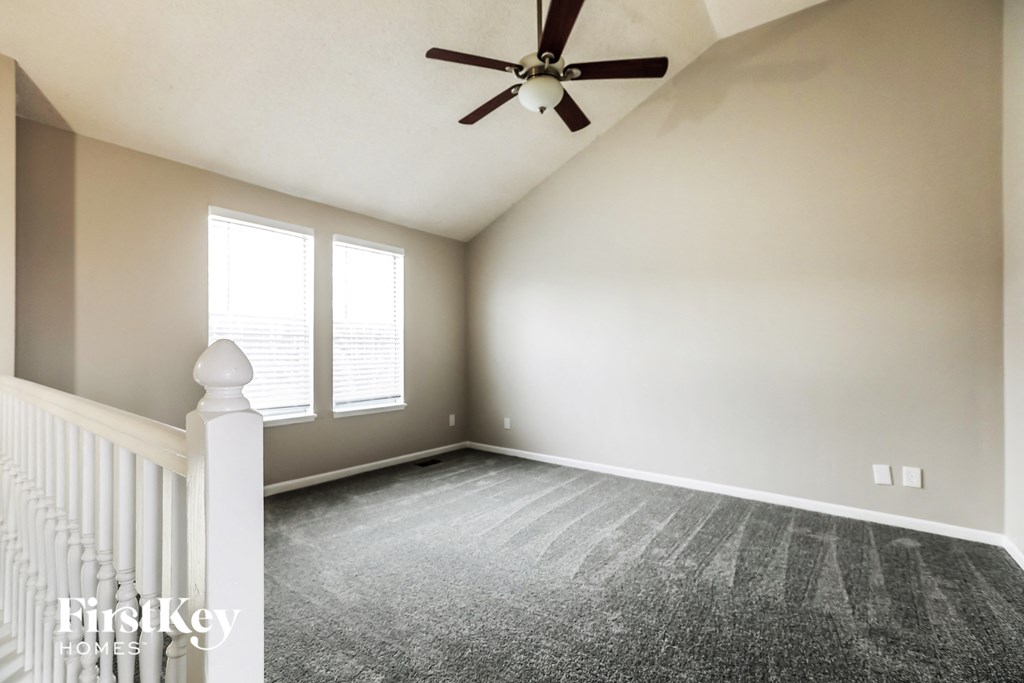 an empty bedroom with a ceiling fan and windows