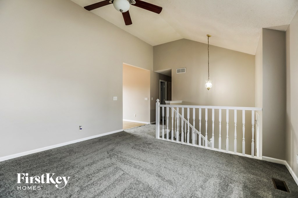 an empty living room with a staircase and a ceiling fan