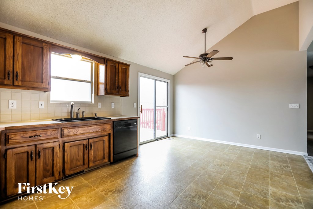 the kitchen and living room of an empty house with a ceiling fan