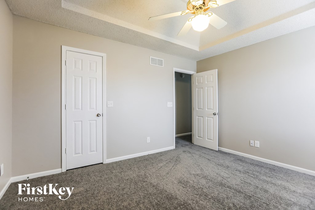 a bedroom with two doors and a ceiling fan