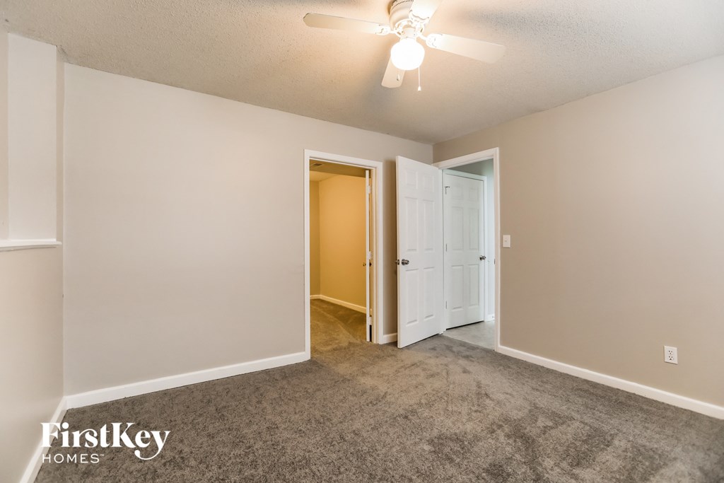 a empty living room with a ceiling fan and a door to a closet