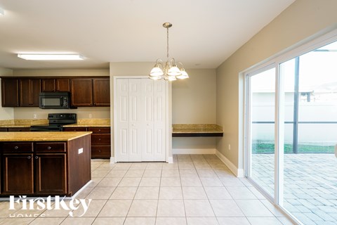 A kitchen with brown cabinets and a black microwave.