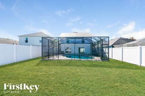A backyard with a pool and a white fence.