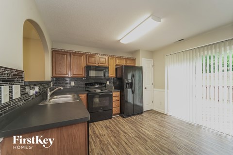 A kitchen with a black fridge and a black stove top oven.