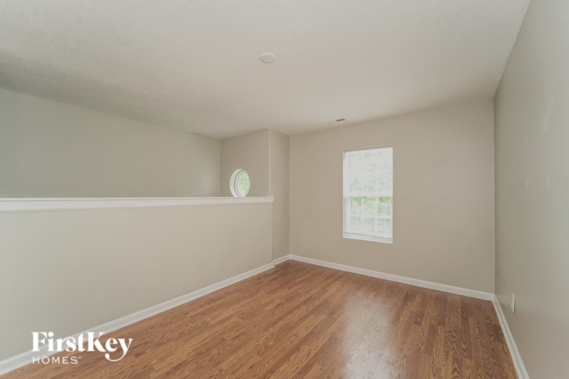 a bedroom with wood floors and white walls and a window