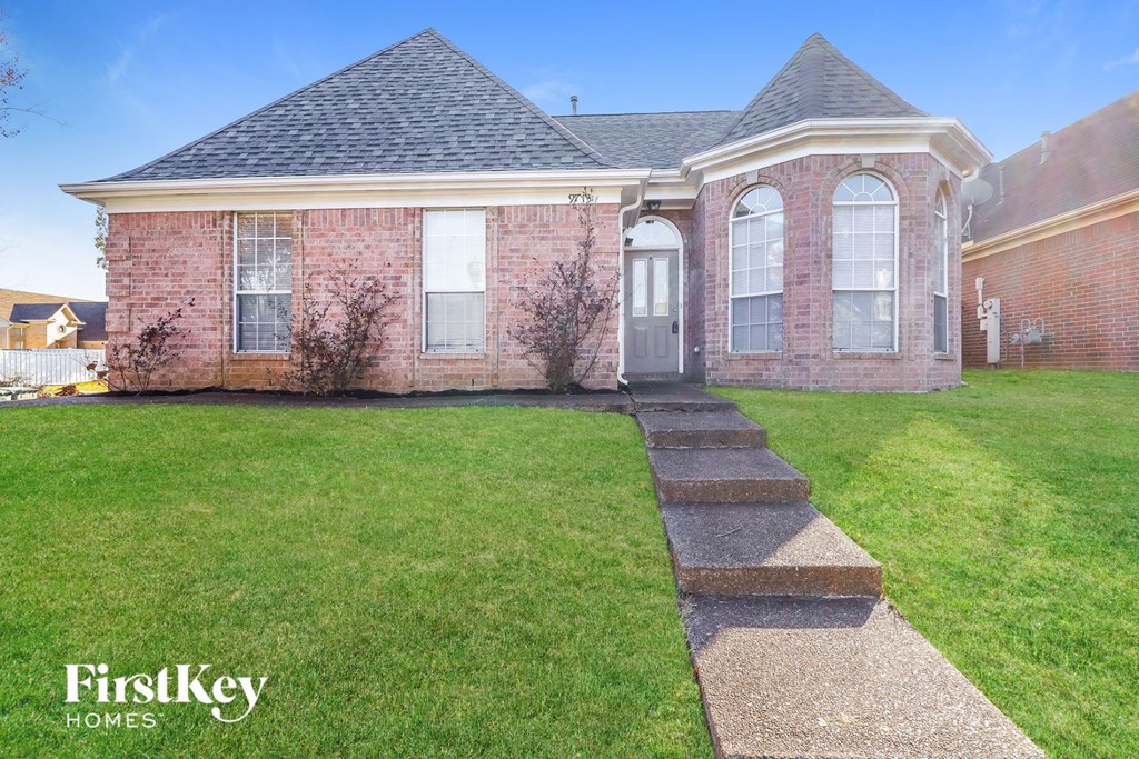 the front of a brick house with a lawn and grass