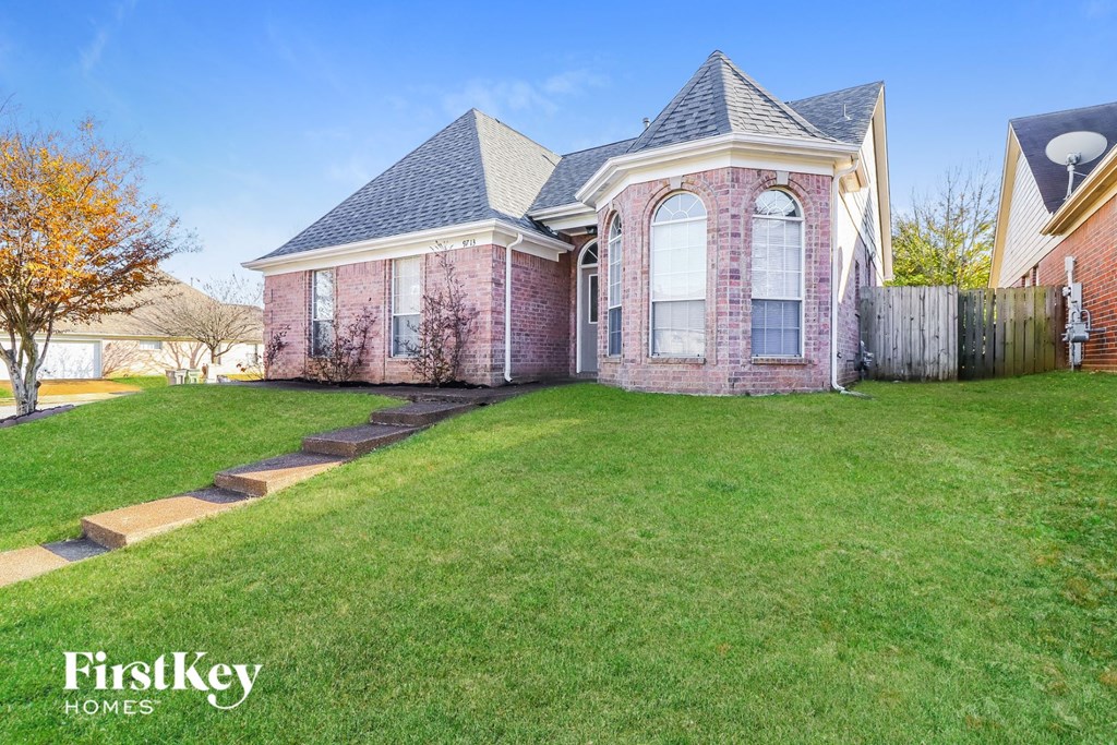 a home with a lawn and a fence in front of it