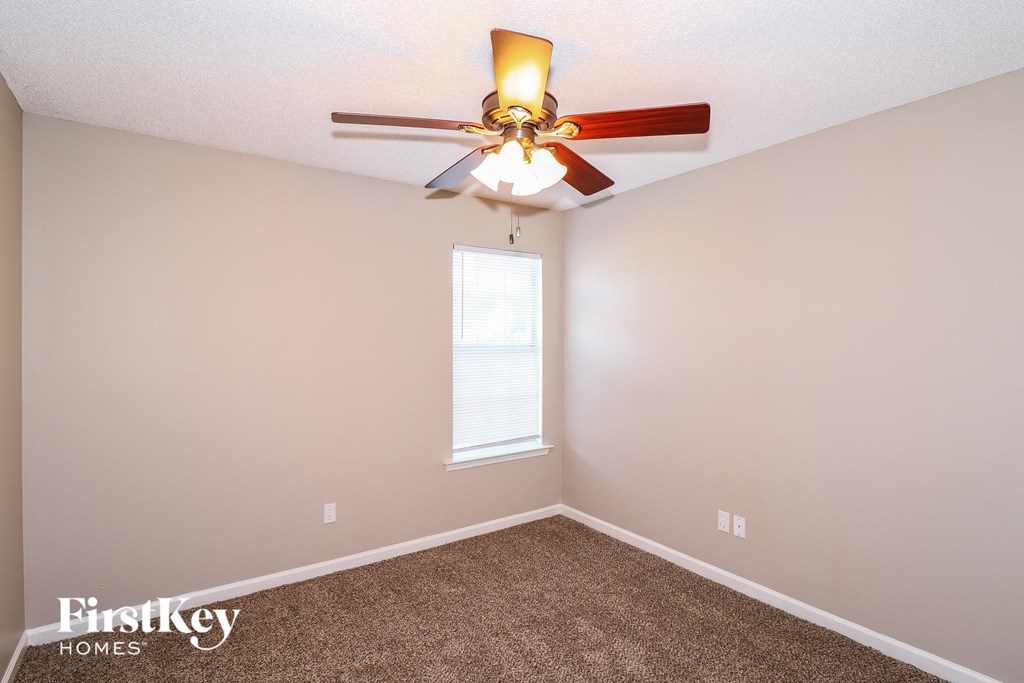 a bedroom with a ceiling fan and a carpet