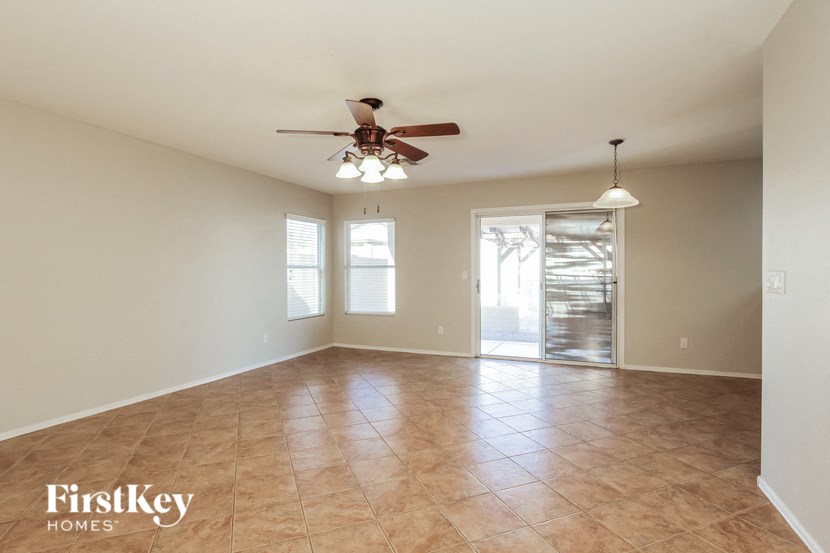 an empty living room with a ceiling fan and tiled floors