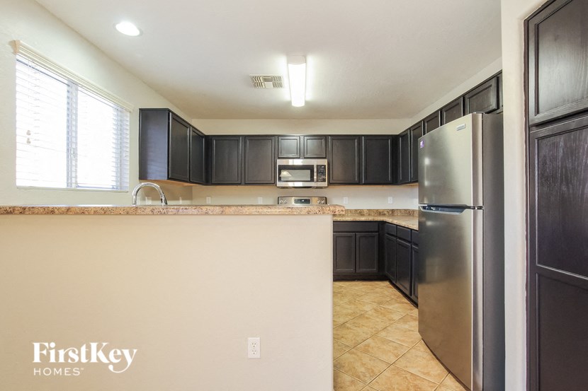 an empty kitchen with black cabinets and a stainless steel refrigerator