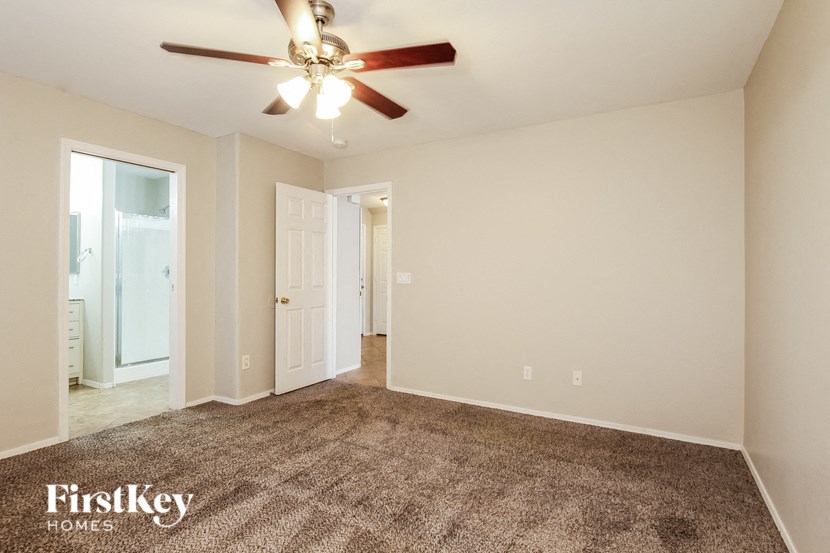 a spacious living room with carpet and a ceiling fan