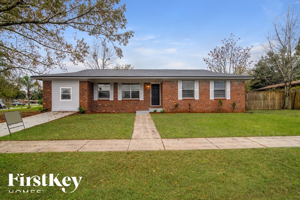 a small brick house with a lawn and a sidewalk