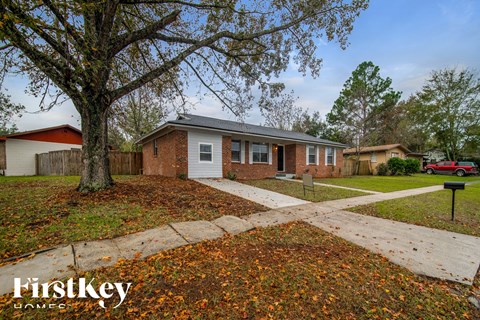 a home with a sidewalk and a tree in front of it