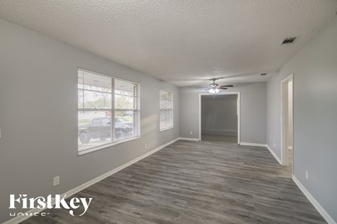 the living room of an apartment with a wood floor and a ceiling fan