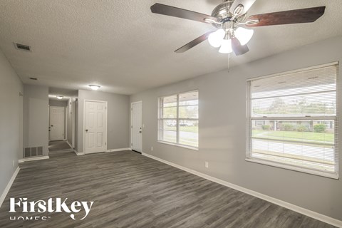 the living room of an empty house with a ceiling fan