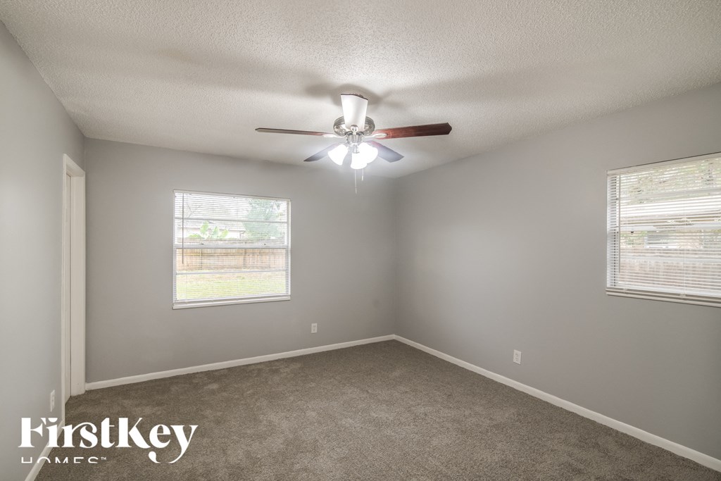 a bedroom with a ceiling fan and two windows