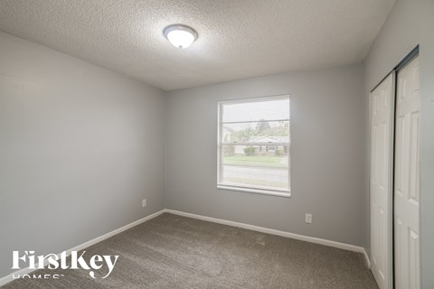 a bedroom with a window and a carpeted floor