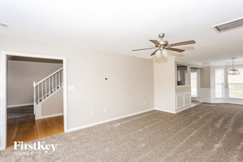A spacious room with a carpeted floor and a ceiling fan.