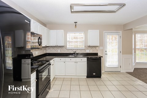 A kitchen with black appliances and white cabinets.