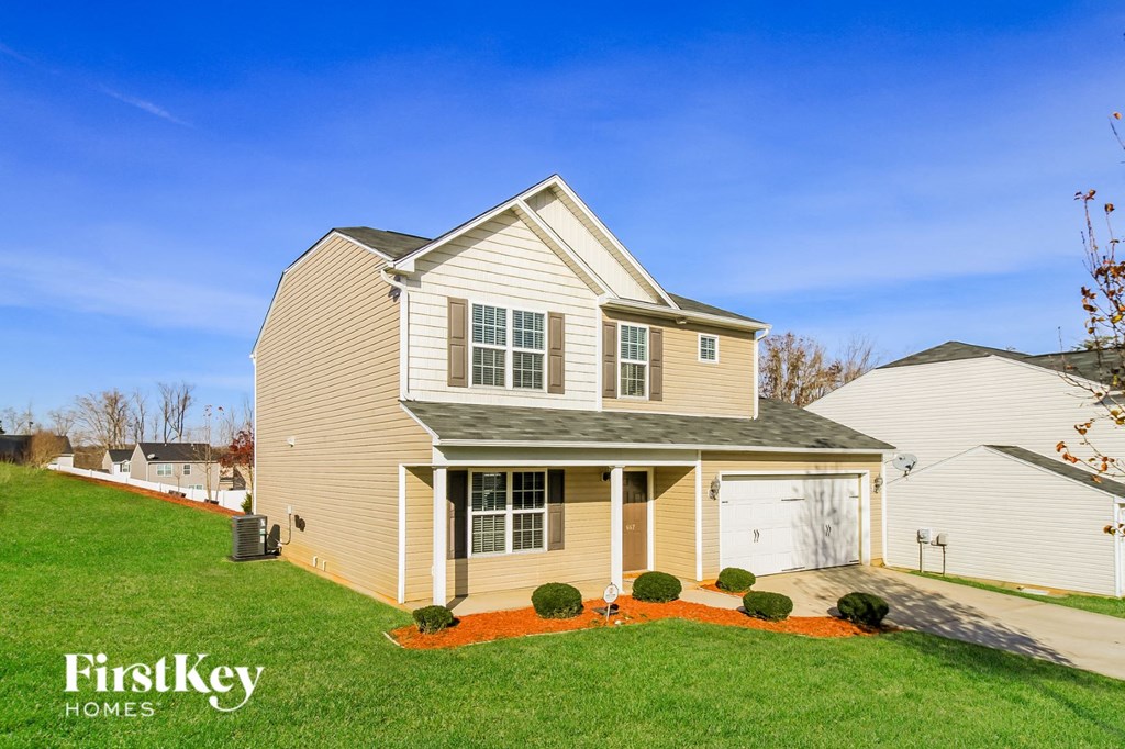 a yellow house with a lawn and a white garage