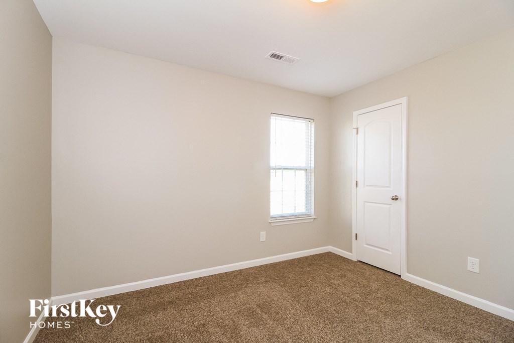 a bedroom with white walls and a white door and a window