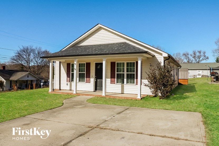 a small white house with a sidewalk in front of it