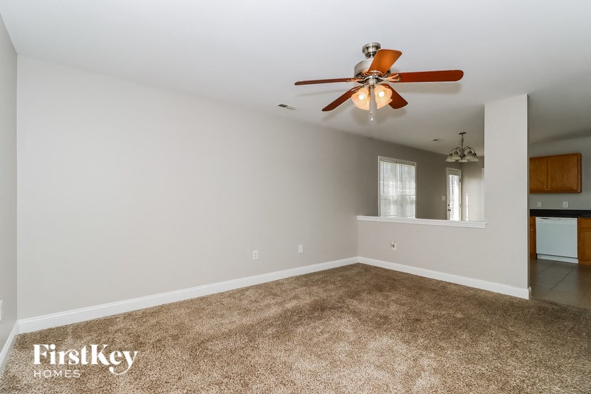 a empty living room with a ceiling fan and a carpet