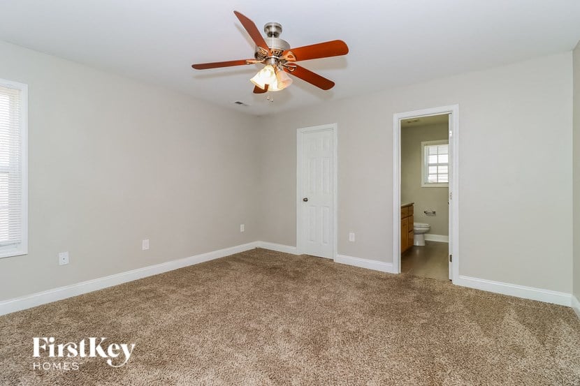 the master bedroom has a ceiling fan and a carpeted floor