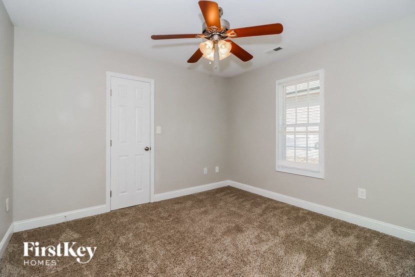 the master bedroom has a ceiling fan and a carpeted floor