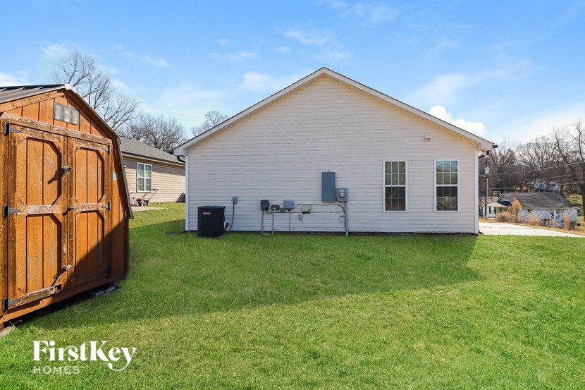a backyard with a white house and a wooden shed