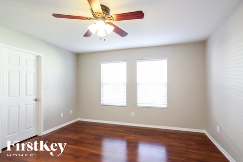 a bedroom with a ceiling fan and two windows
