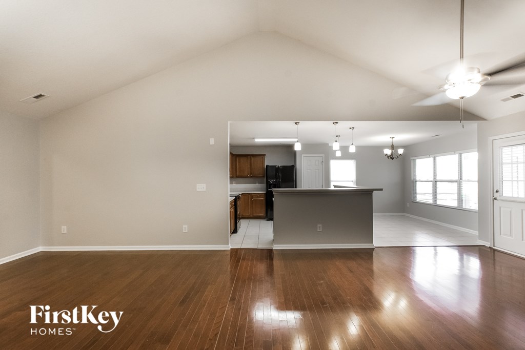 A spacious room with wooden floors and a ceiling fan.