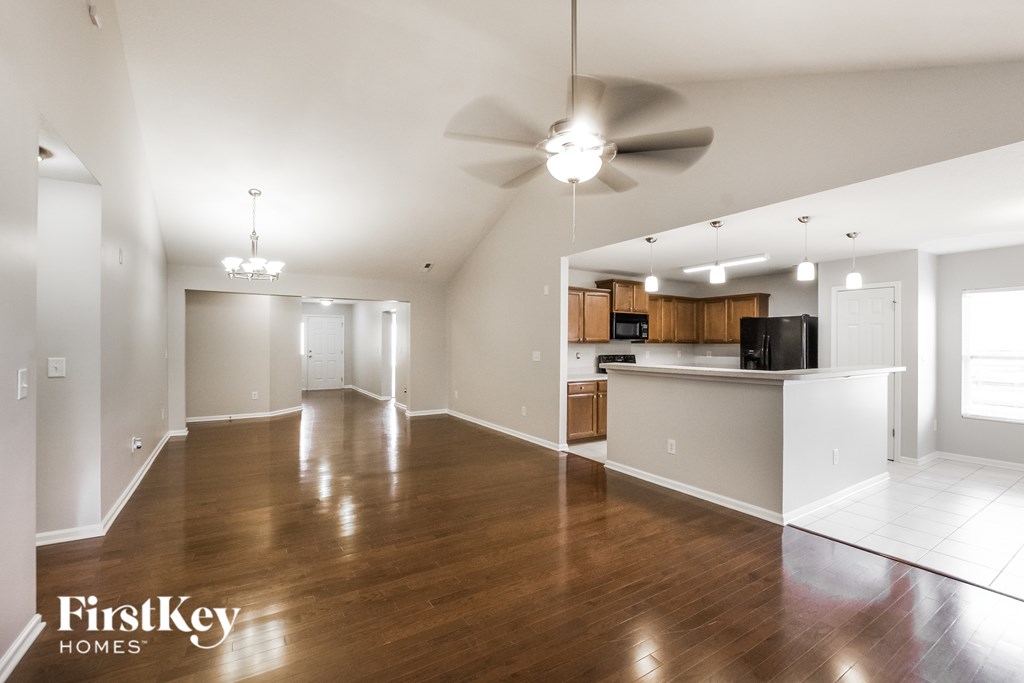 A spacious living room with wood floors and a ceiling fan.