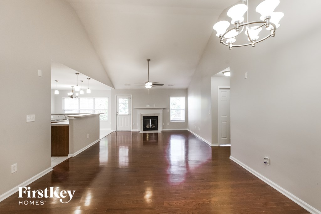 A spacious room with wooden floors and a chandelier hanging from the ceiling.