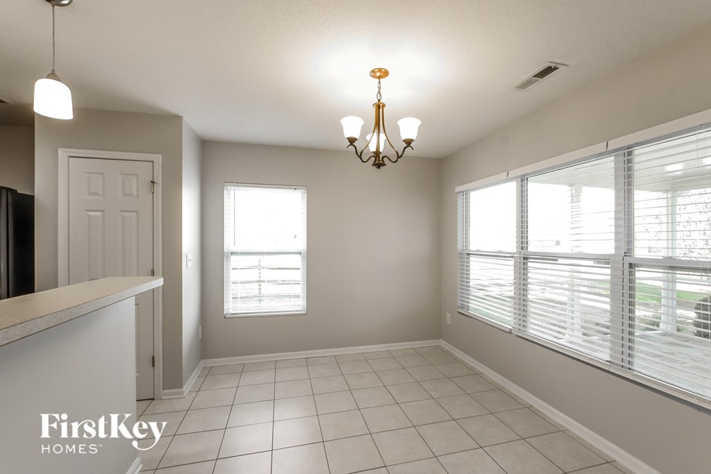 A room with a chandelier and a window with blinds.