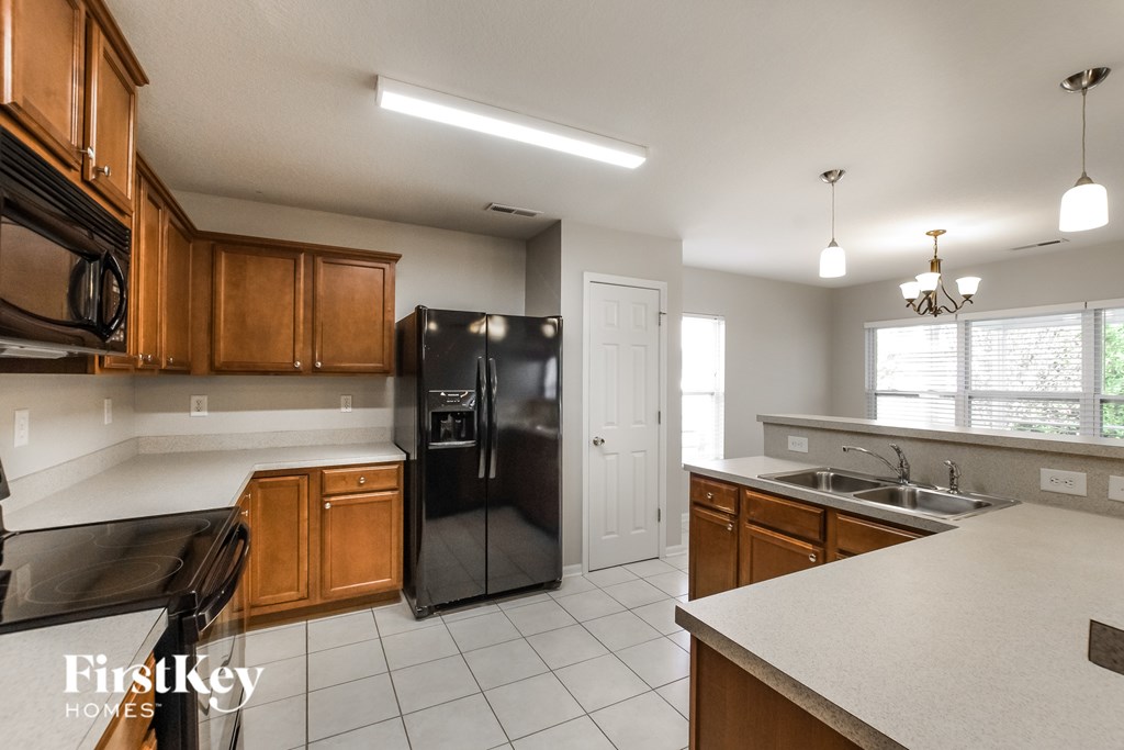 A kitchen with a black fridge and wooden cabinets.