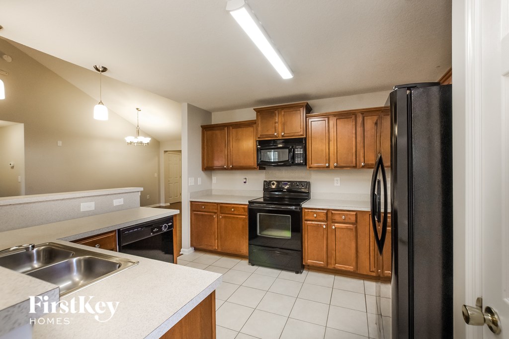 A kitchen with a black refrigerator and wooden cabinets.