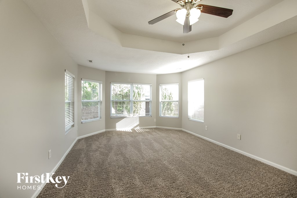 A spacious room with a carpeted floor and a ceiling fan.