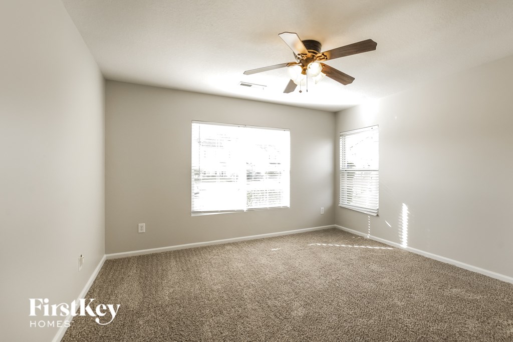 A room with a ceiling fan and two windows.