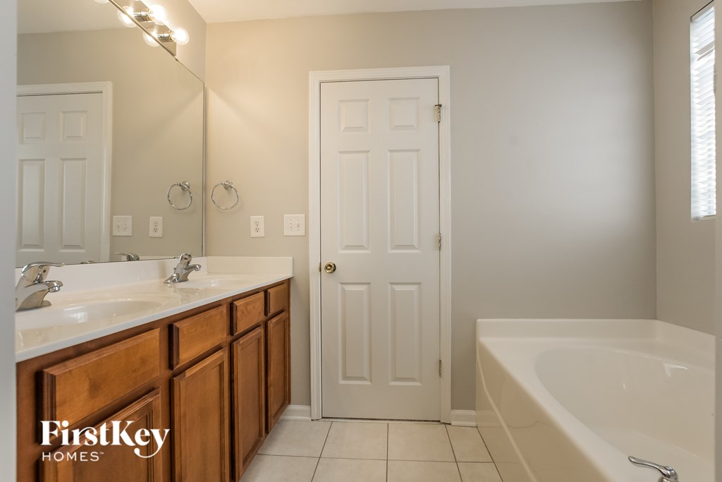 A bathroom with a tub, sink, and mirror.