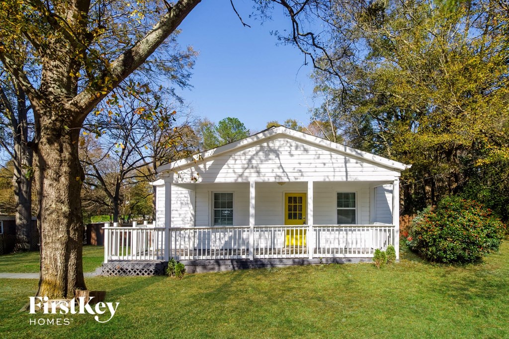 a small white house with a yellow door and a porch