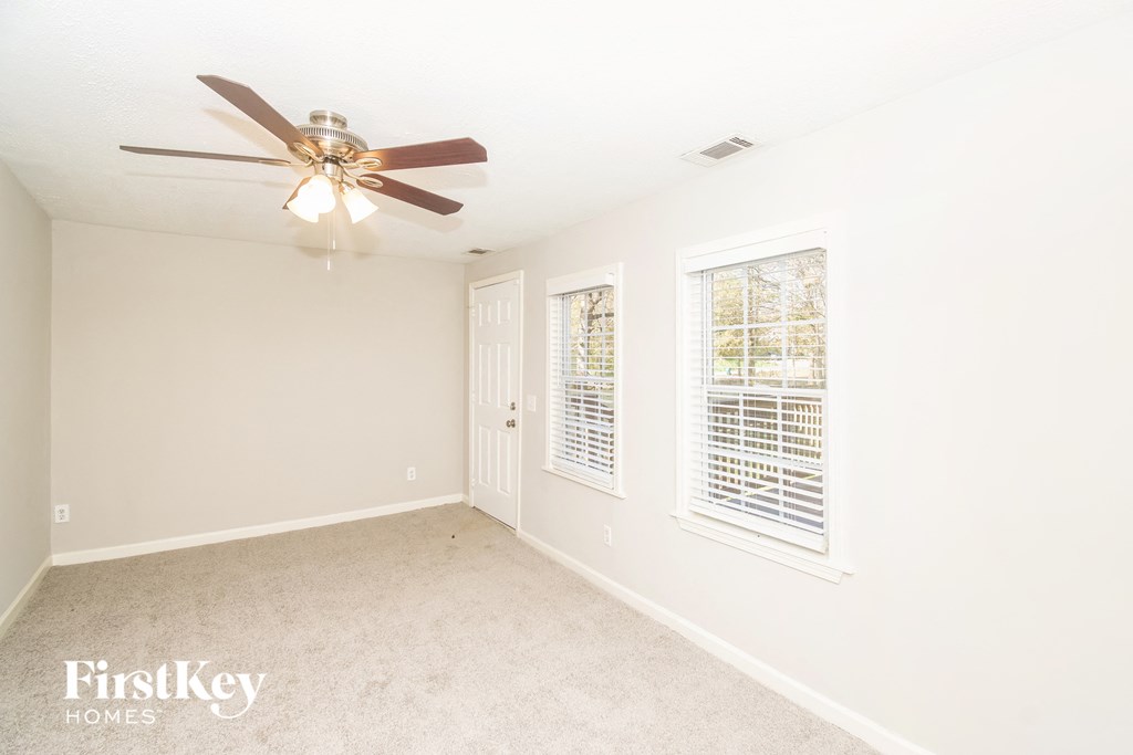 a bedroom with white walls and a ceiling fan
