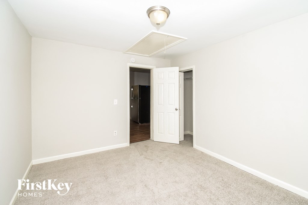 a bedroom with white walls and carpet and a door to a hallway