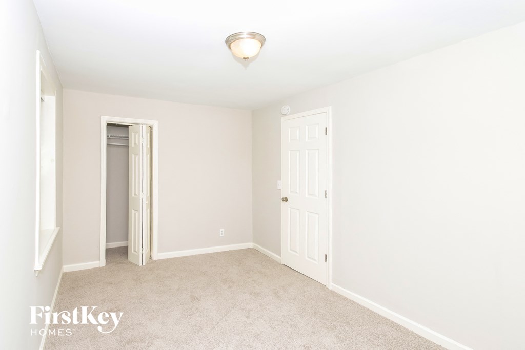 a bedroom with white walls and a white door and carpet