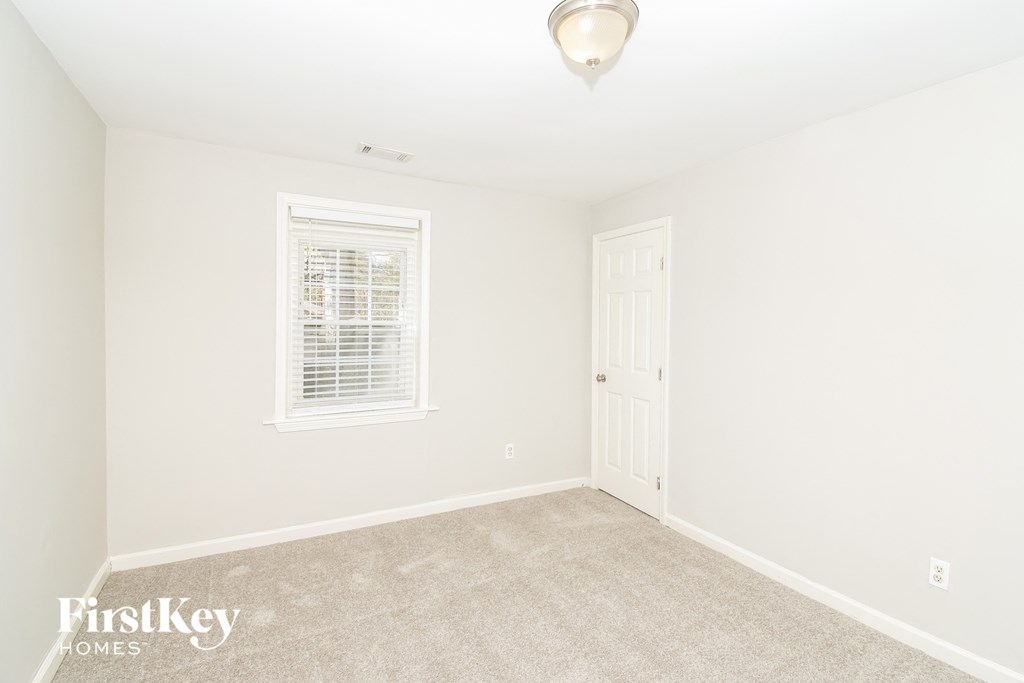 a bedroom with white walls and carpet and a white door